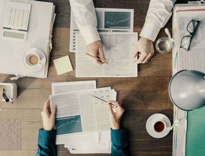 Business people working together and checking financial charts, top view